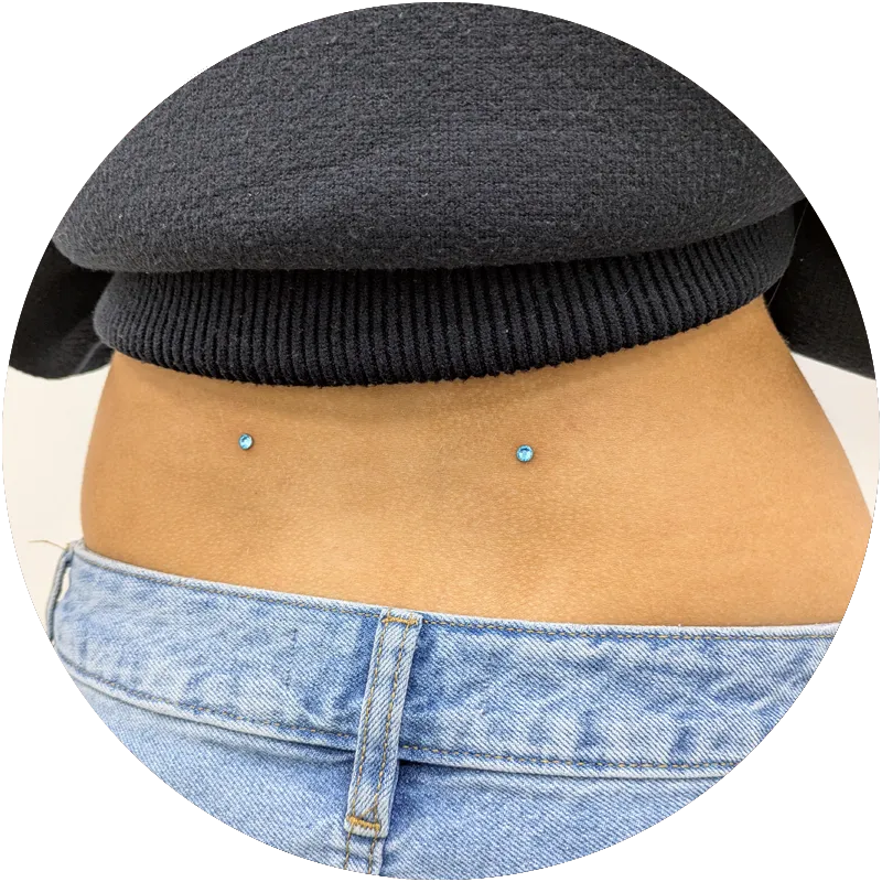 A pair of dermal piercings on a clients back