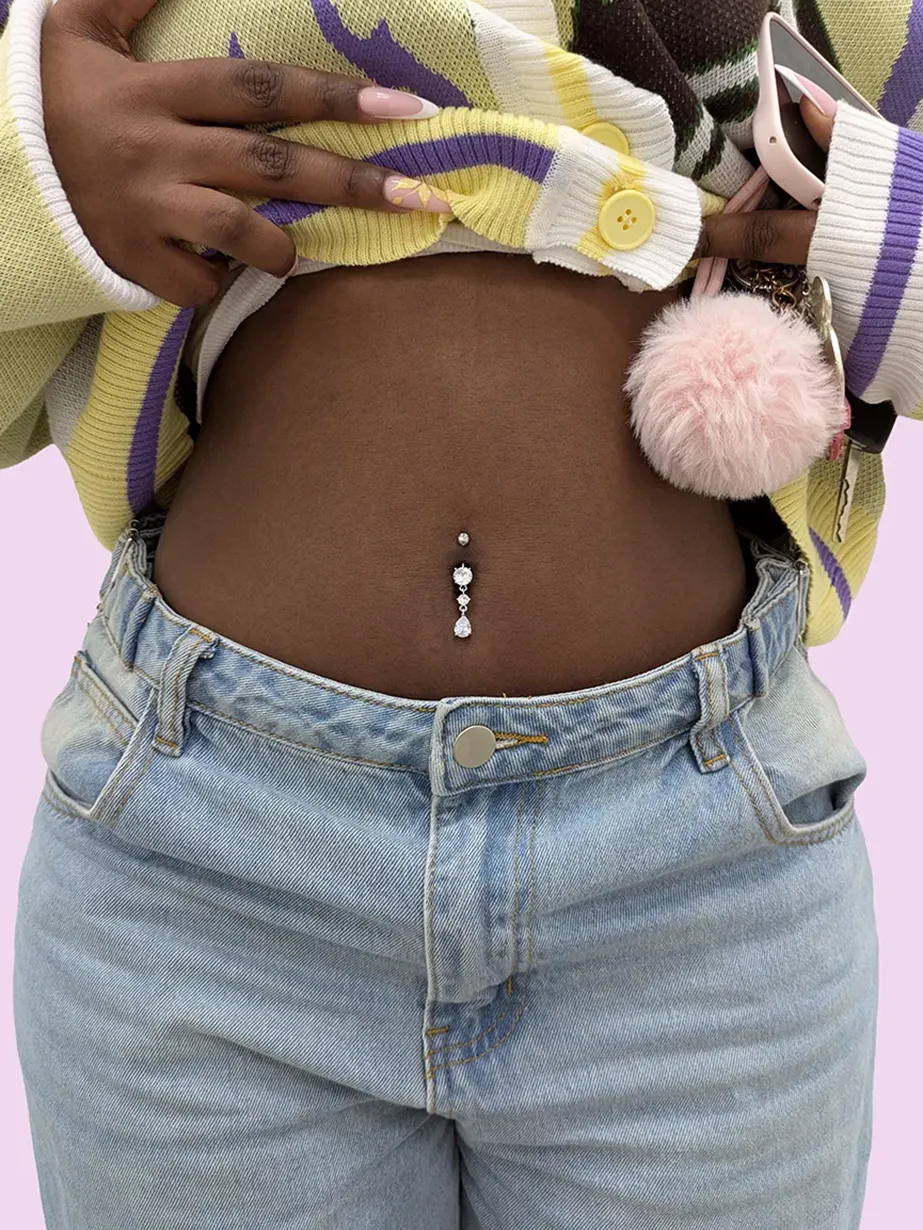Close up of a woman with yellow top and jeans with a belly button piercing