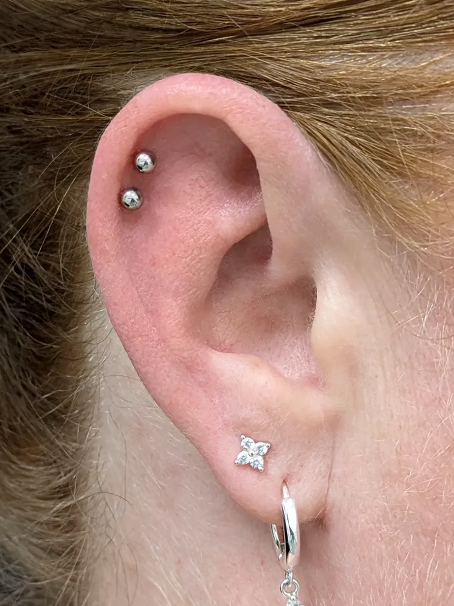 Close up of an ear with a pair of helix piercings