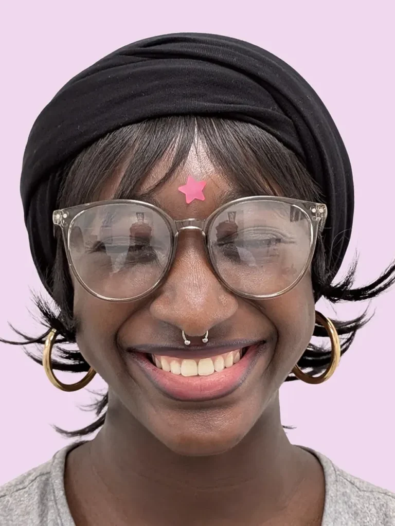 Portrait of a smiling person with glases and a septum piercing