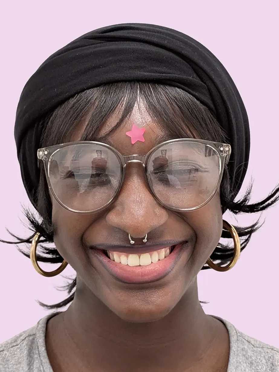 Portrait of a smiling person with glases and a septum piercing