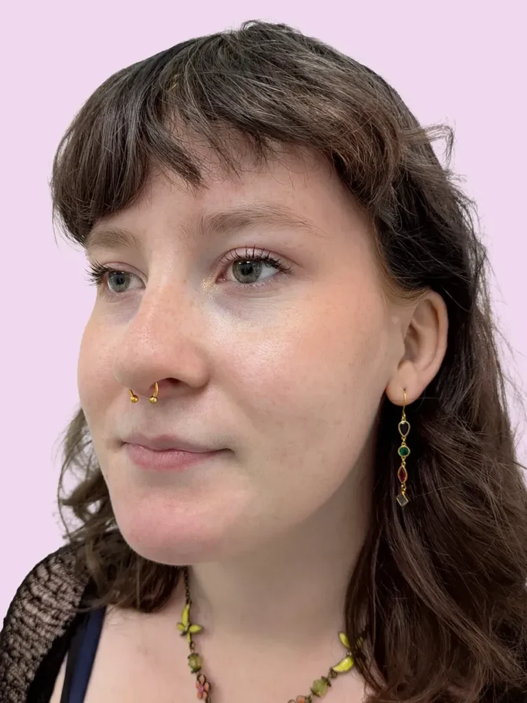 Portrait of a woman with brown hair and a gold septum piercing