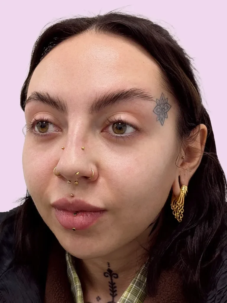 Portrait of a woman with brown hair and multiple facial piercings
