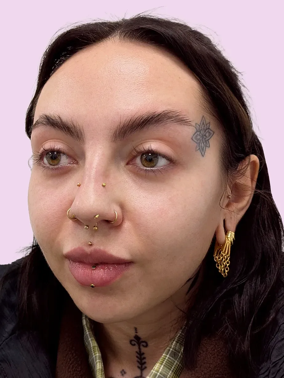 Portrait of a woman with brown hair and multiple facial piercings