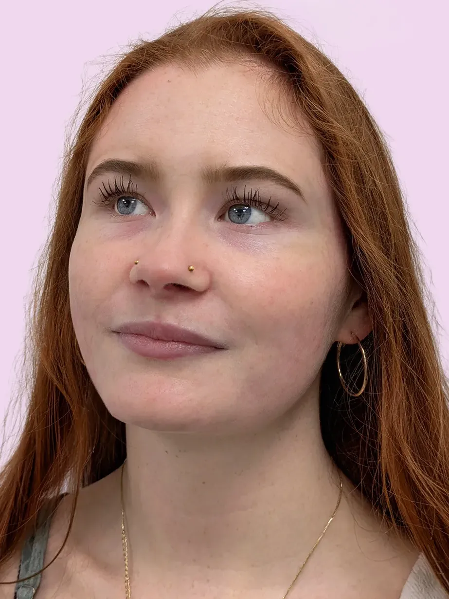Portrait of a woman with red hair and pair of gold nostril piercings