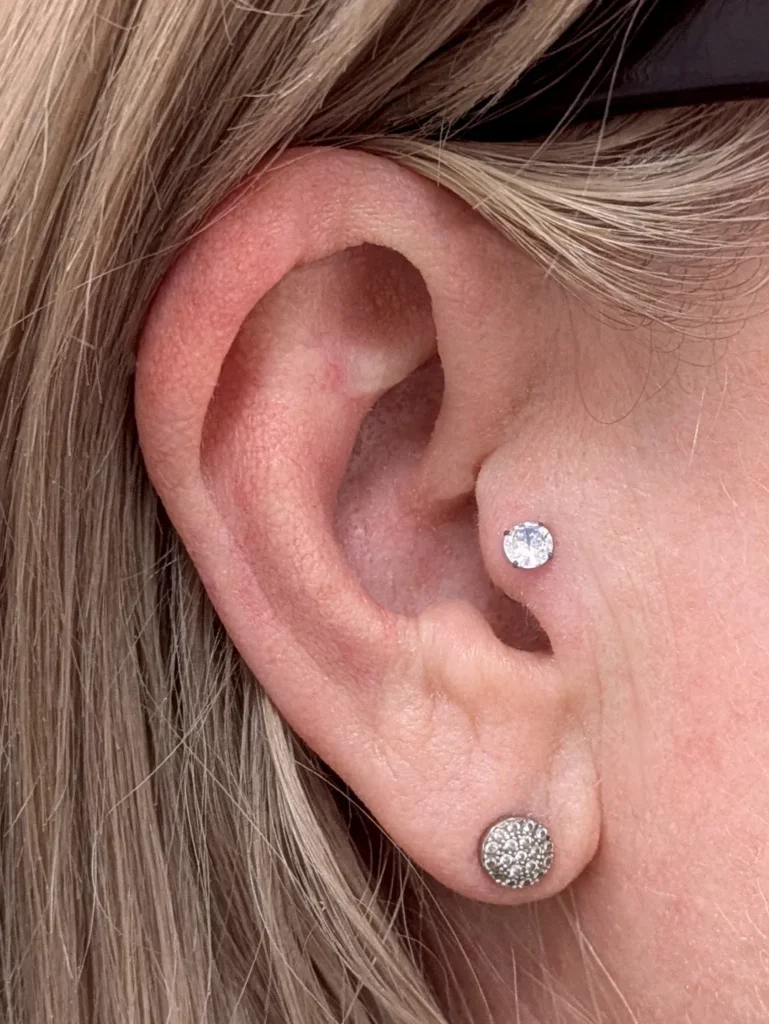 Close up of an ear with a trugus piercing with gem set jewellery