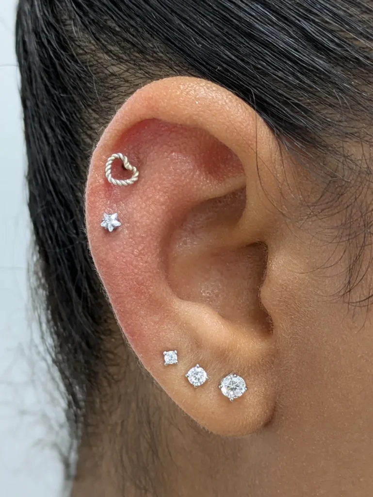 Close up of an ear with two decorative helix piercings and two earlobe piercings