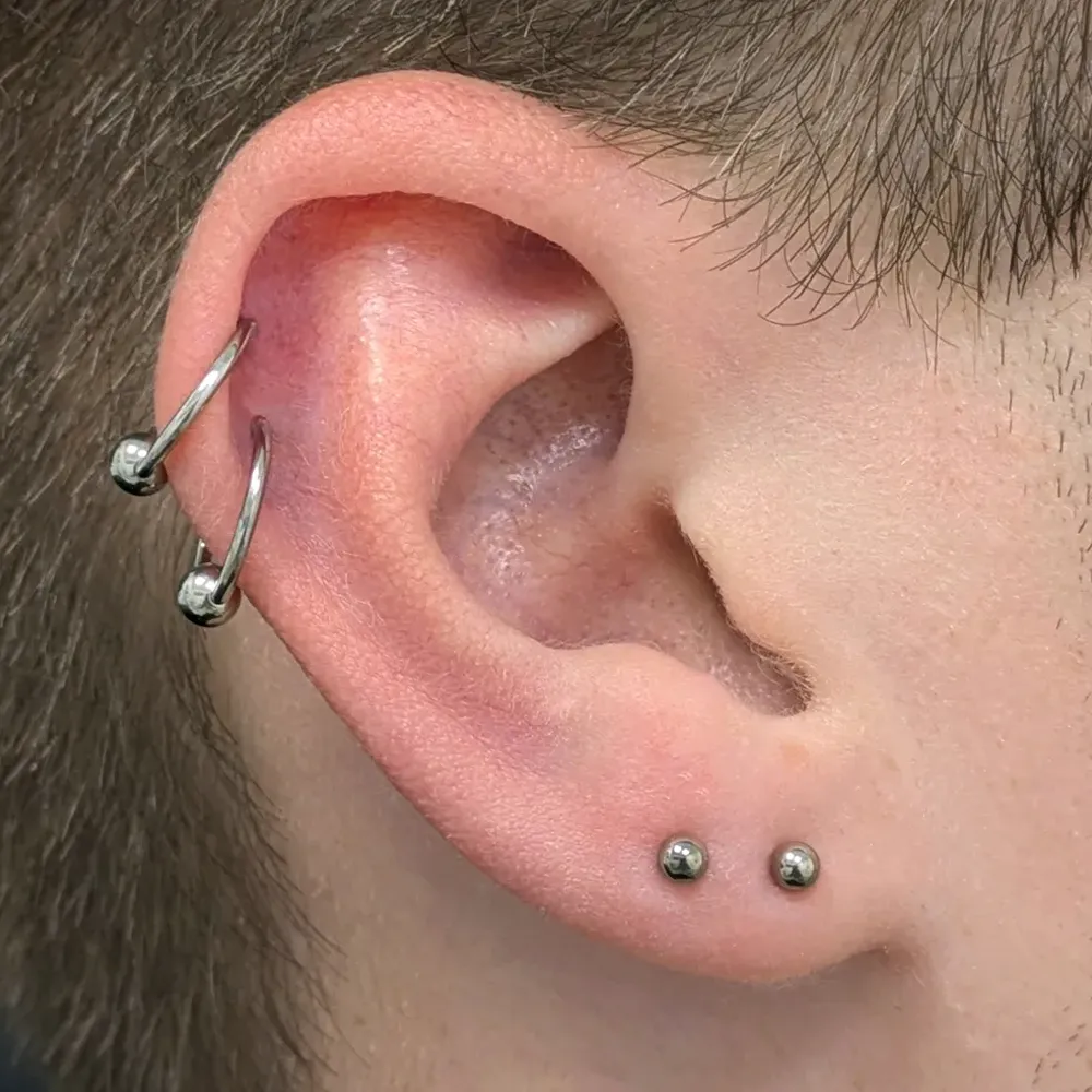 Close up of an ear with two helix piercings and two earlobe piercings